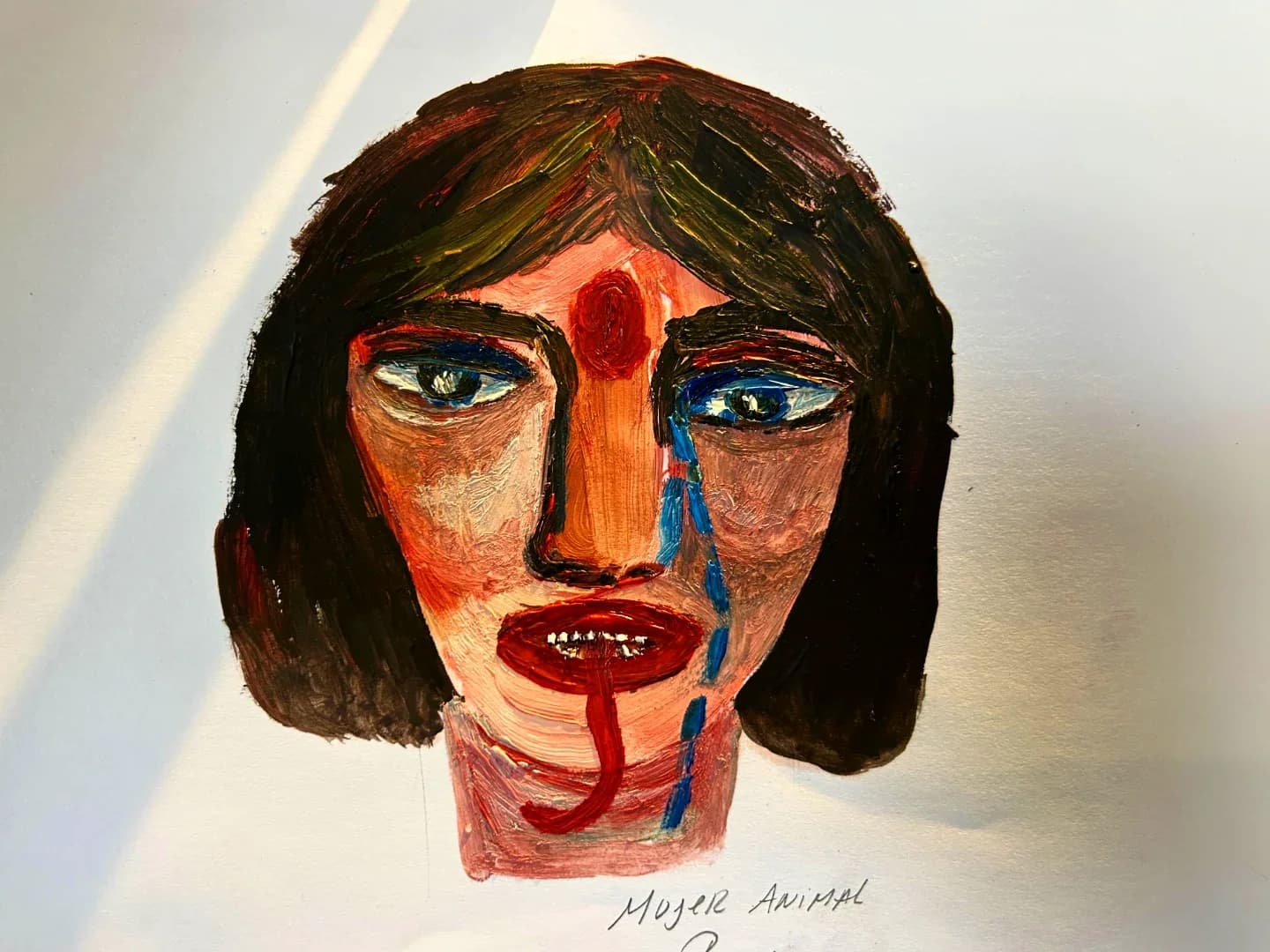 Rostro de mujer con lágrimas azules y pómulos rojos, pintado sobre papel, con el título escrito a mano.